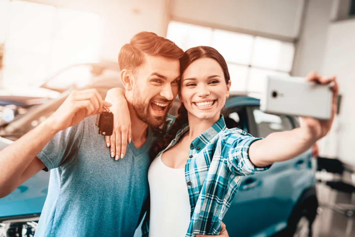 A Man And A Woman Do Selfie Near Their New Car.