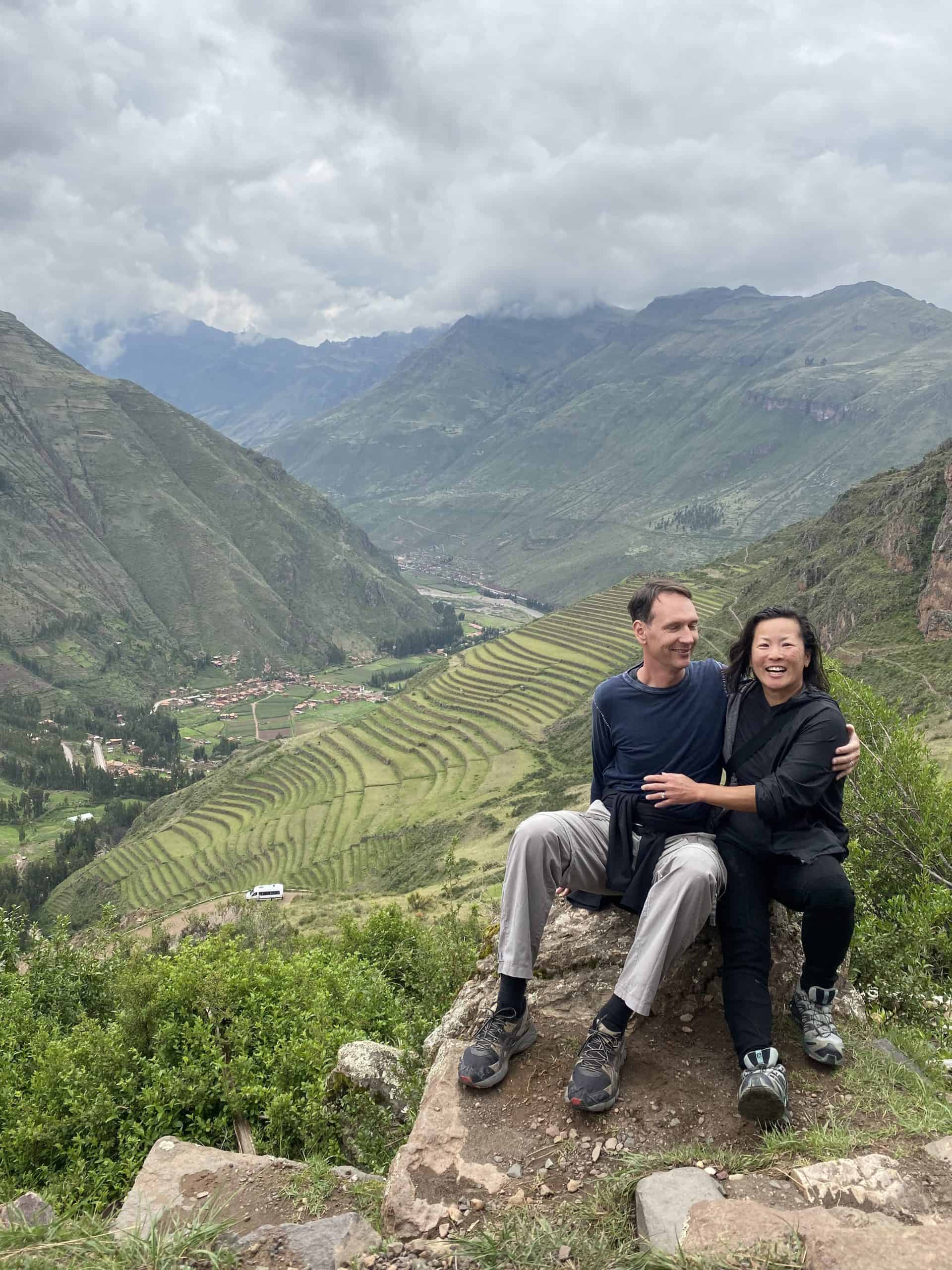 A couple enjoying a moment with a stunning view of lush, terraced hills and a valley in the background.