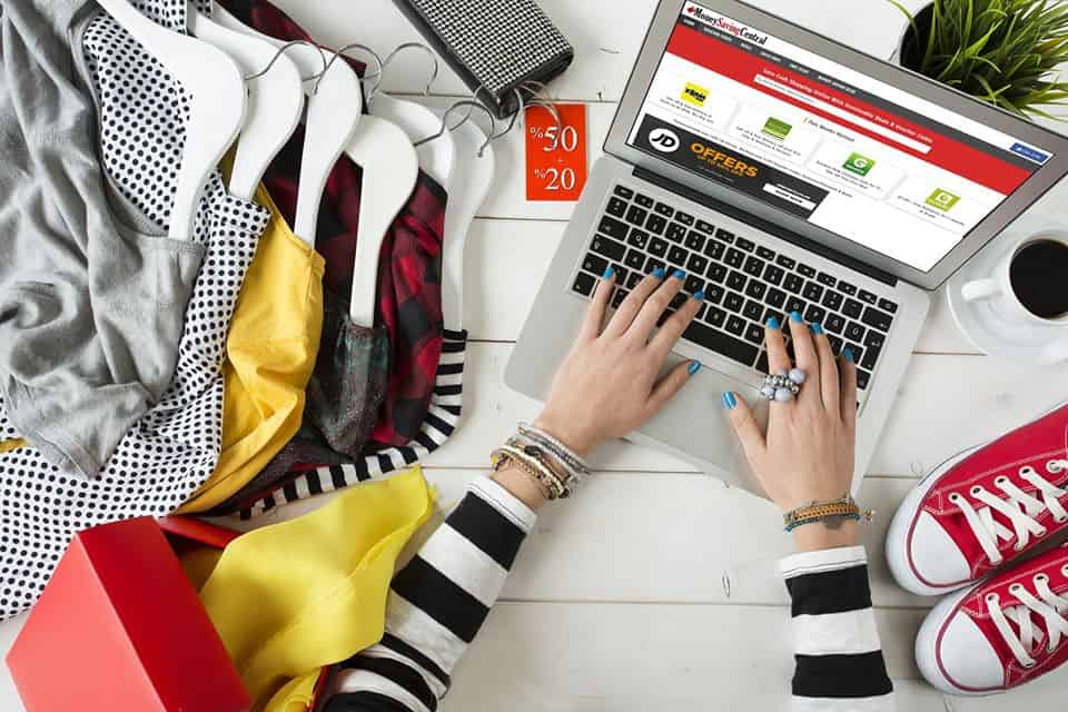 Online shopping spree: a person amidst a vibrant array of clothes, deals, and a fashion-focused web page, orchestrates a modern retail therapy session from the comfort of home.