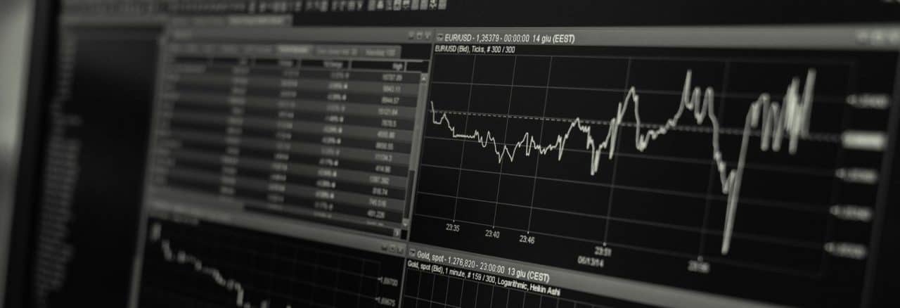 A shallow depth of field view of financial data on a computer monitor showing a fluctuating stock market chart.