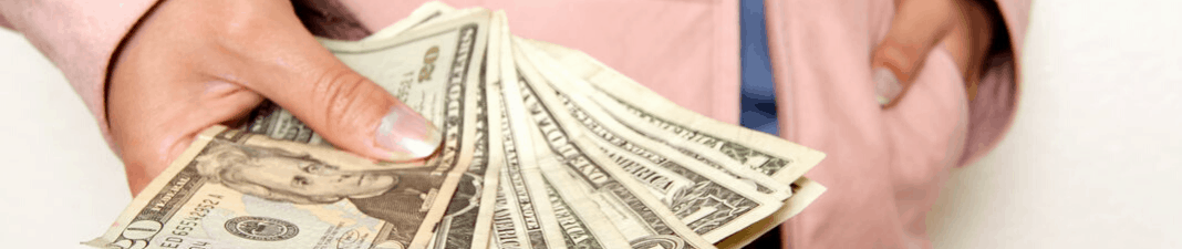 Person holding a fan of us dollar bills, suggesting a concept of wealth, savings, or financial transactions.