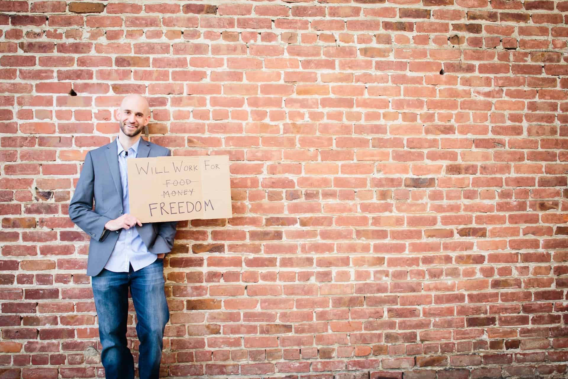 A man in a suit holding a cardboard sign with the words 