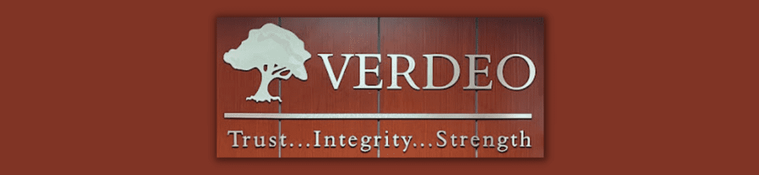 Elegant business signage featuring the name 'verdeo' with a tree emblem, set against a rich wooden background, and underlined with the words 'trust. integrity... strength.'.