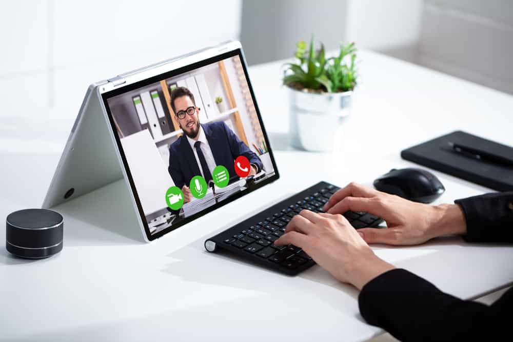 A woman meeting with her financial advisor online, typing on a keyboard, using a tablet computer.