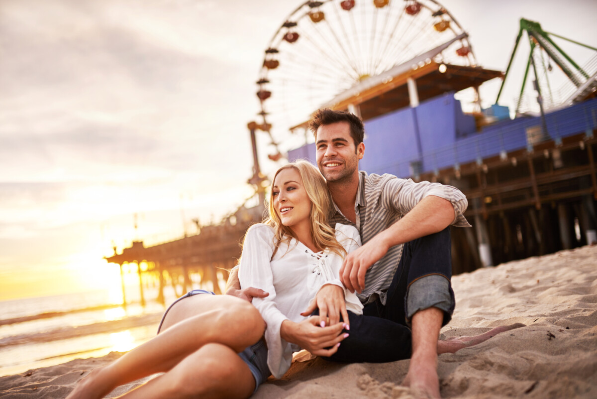 happy romantic couple at santa monica during sunset on the beach, celebrating their time in one of the best beach towns in California.