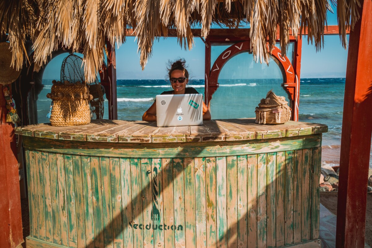 A digital nomad works from a cabana on the beach.
