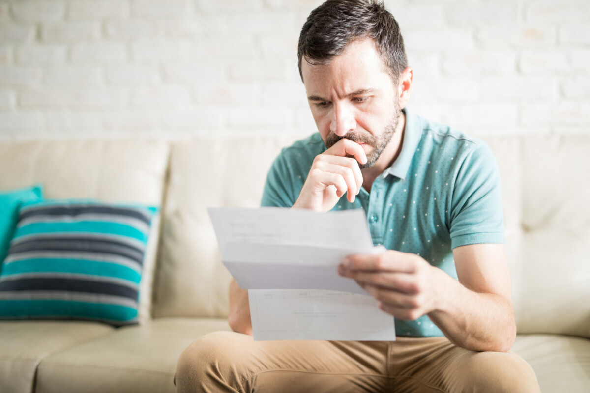 A man looks at a bill, wondering what has increased his total loan balance.