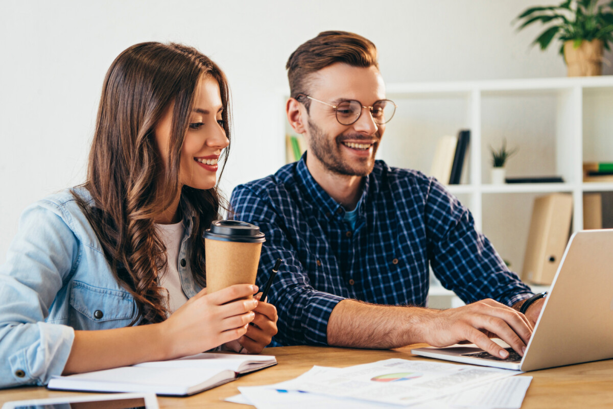 Man and woman couple looking at laptop together smiling as they receive online education