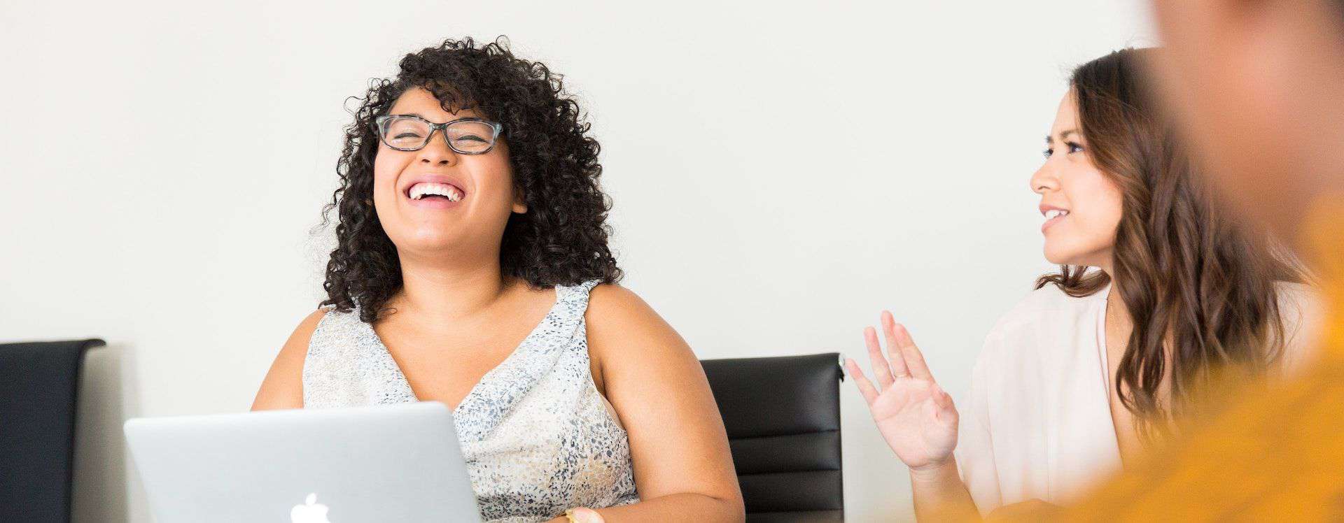 Joyful collaboration: a woman laughing and enjoying a lively discussion with a colleague during a meeting.