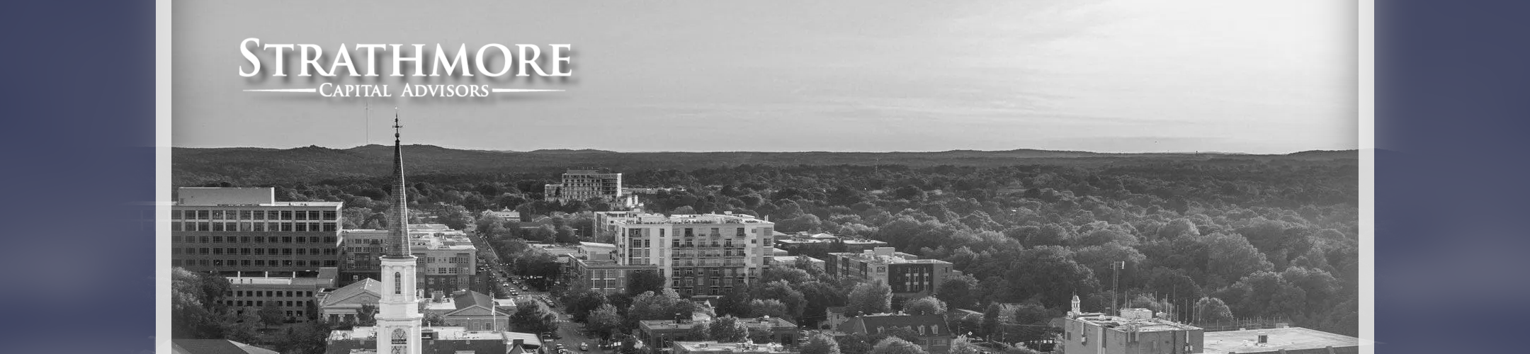 A grayscale aerial view of a small city with trees and buildings; text at the top left reads 