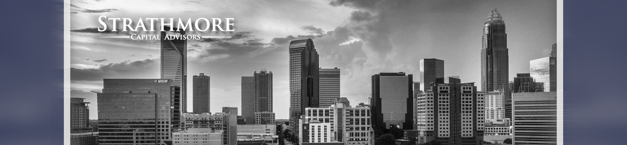 Black-and-white city skyline with tall modern buildings under a dramatic sky. 